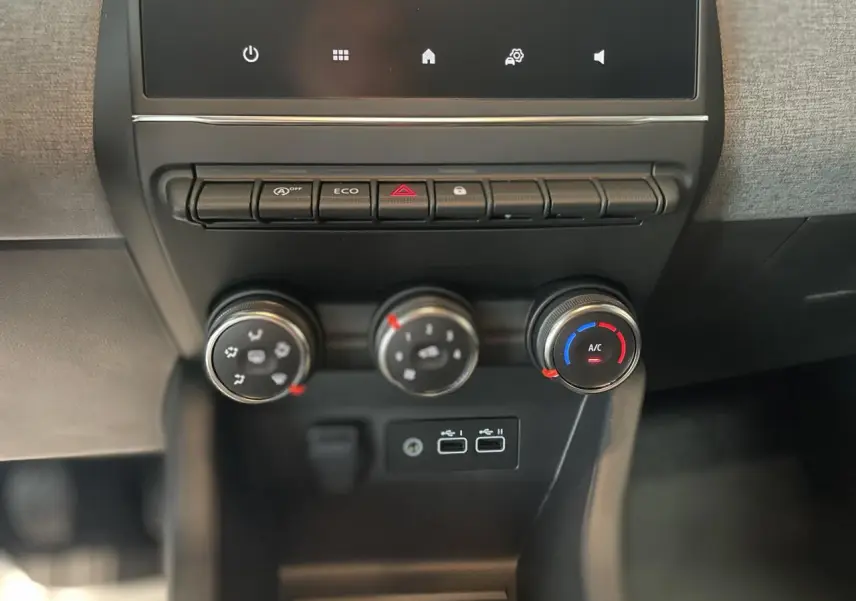 Gros plan sur la console centrale de la Renault Clio 2025 blanche, montrant les commandes de climatisation et les ports USB.