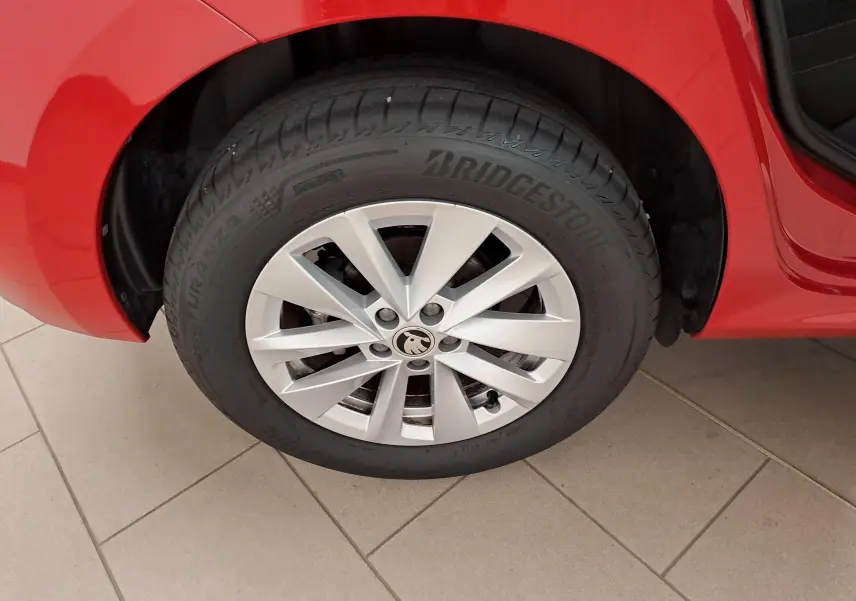Gros plan sur la roue avant gauche d'un Skoda Kamiq 2024 Rouge Velvet avec jante argentée et pneu Bridgestone.