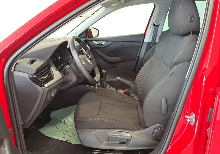 Vue intérieure côté conducteur du Skoda Kamiq 2024 rouge Velvet, montrant les sièges en tissu et le volant avec Virtual Cockpit.