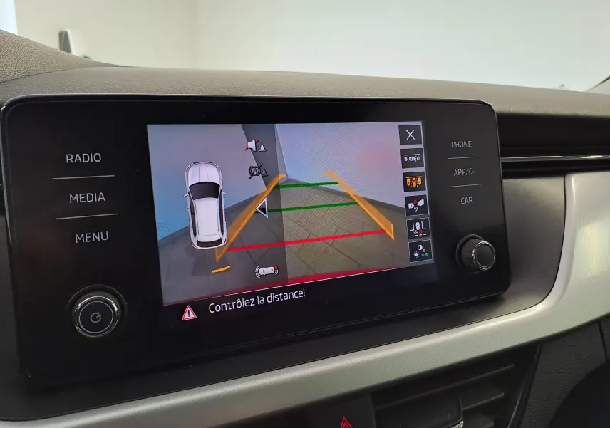 Écran central du Skoda Kamiq 2024 affichant la caméra de recul avec lignes de guidage colorées.
