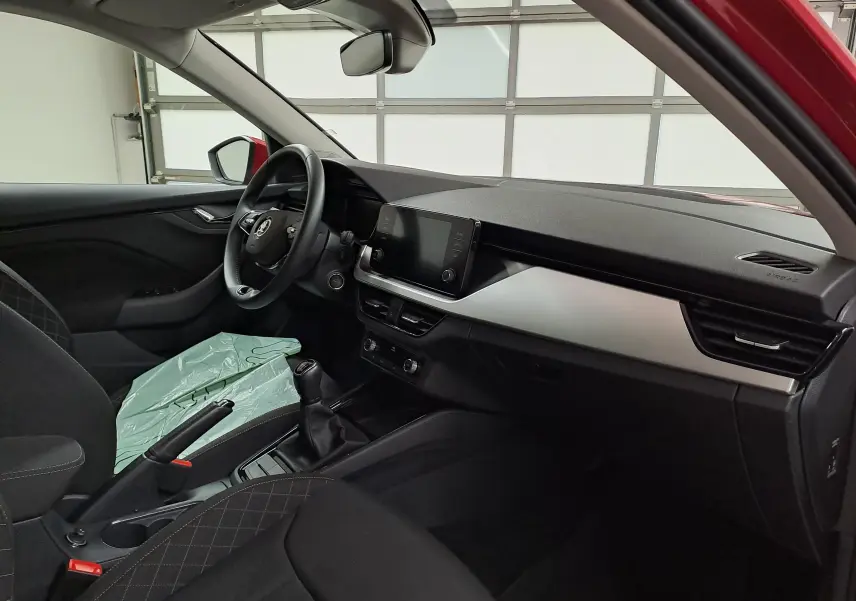 Intérieur du Skoda Kamiq 2024 vu côté conducteur, tableau de bord moderne avec écran tactile et volant multifonction.