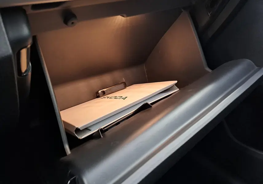 Gant de rangement ouvert côté passager du Skoda Kamiq 2024 avec manuel du véhicule visible à l'intérieur.