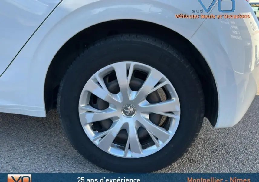 Gros plan sur la roue arrière droite blanche d'une Peugeot 208 1.2 PureTech 2015 avec jante classique 15 pouces.