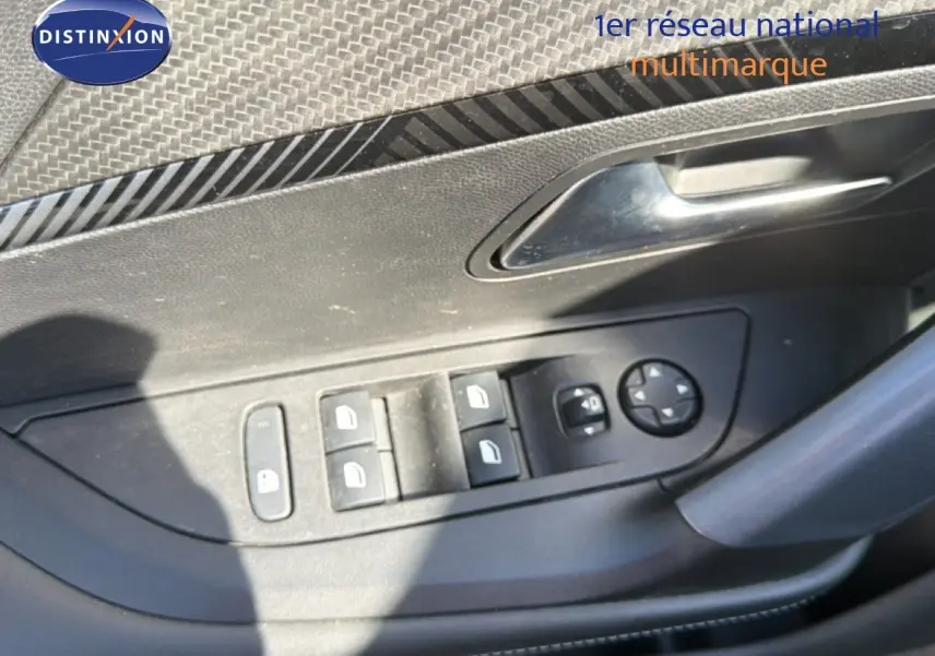Gros plan sur les commandes de lève-vitres et rétroviseurs côté conducteur d'une Peugeot 2008 gris platinium.