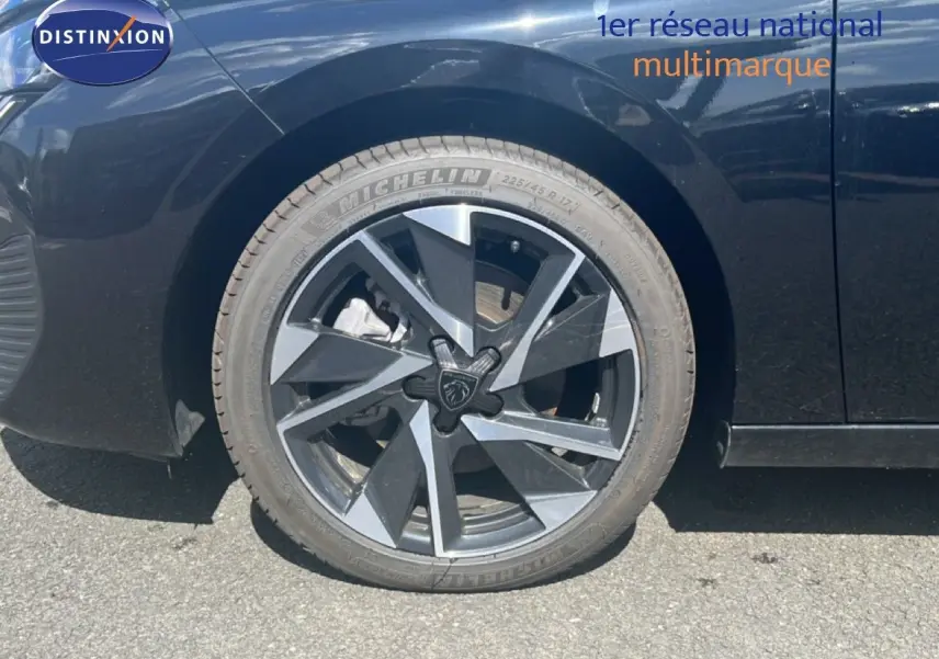Gros plan sur la roue avant gauche d'une Peugeot 308 noir métal avec jante alliage au design moderne.