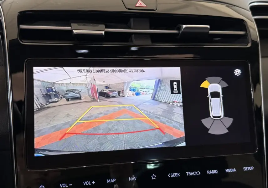 Écran tactile du tableau de bord montrant la caméra de recul et les capteurs de stationnement du Hyundai Tucson noir.