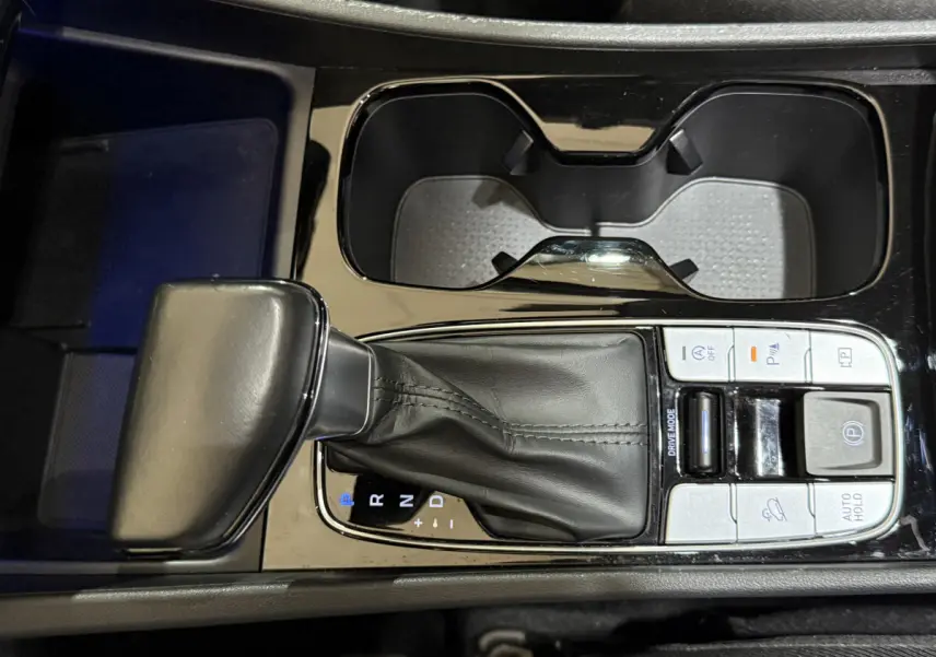 Vue rapprochée de la console centrale noire du Hyundai Tucson 2021, montrant le levier de vitesse automatique et les commandes adjacentes.