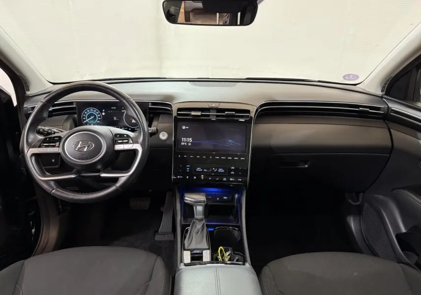 Intérieur noir du Hyundai Tucson 2021 vu de face, avec tableau de bord numérique et écran tactile central lumineux.