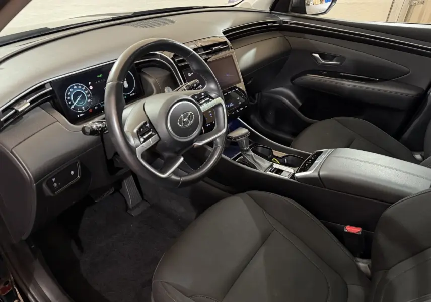 Intérieur noir du Hyundai Tucson 2021 vu côté conducteur, avec tableau de bord numérique et écran tactile central.