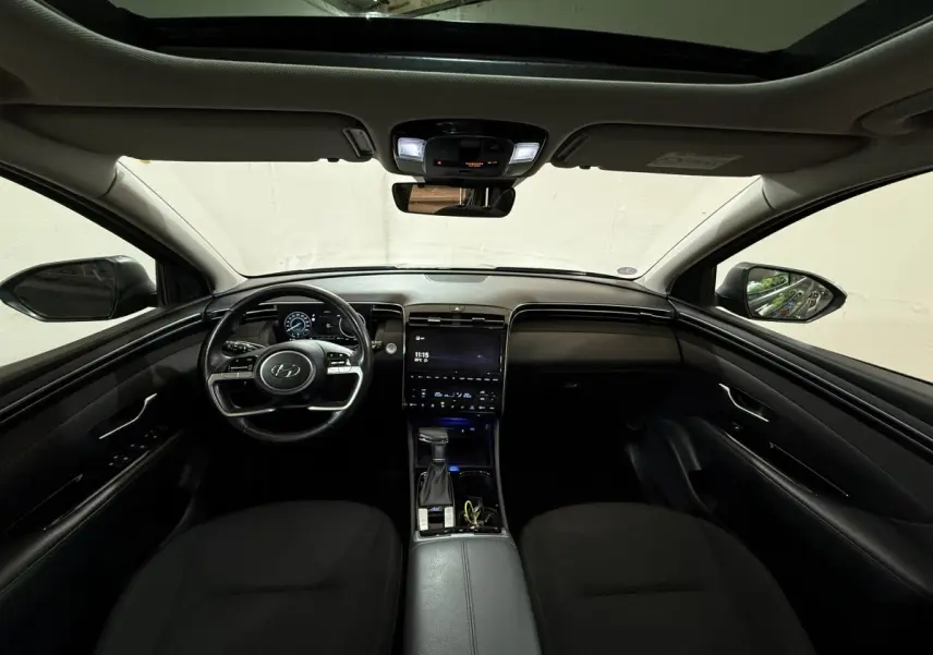 Intérieur noir du Hyundai Tucson 2021, vue frontale du tableau de bord avec écran tactile et volant multifonctions.