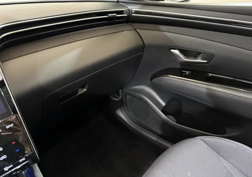 Intérieur côté passager du Hyundai Tucson noir 2021, avec tableau de bord et porte en matériaux noirs élégants.