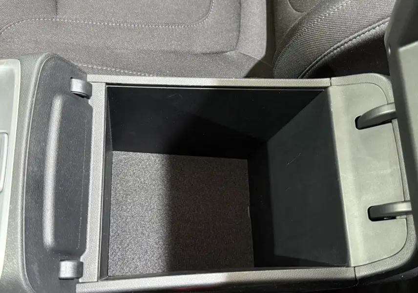 Vue plongeante sur le rangement central ouvert du Hyundai Tucson noir, montrant l'intérieur spacieux et les finitions en tissu.