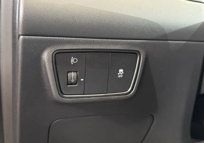 Gros plan sur les commandes de réglage des phares et de l'ESP à gauche du tableau de bord du Hyundai Tucson noir 2021.