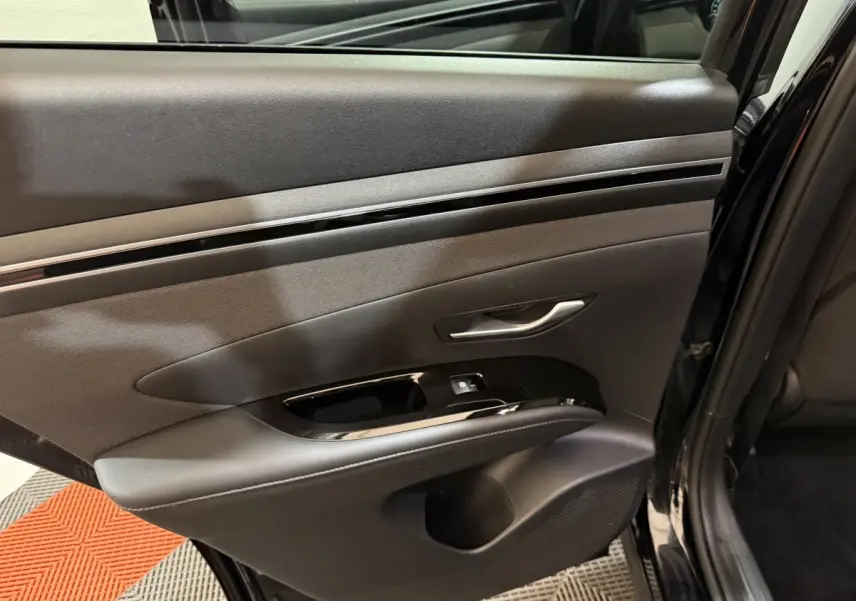 Gros plan sur la porte arrière gauche noire du Hyundai Tucson 2021, avec poignée argentée et commandes de fenêtre intégrées.