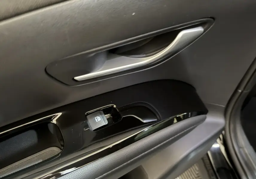 Poignée et commande de lève-vitre côté conducteur du Hyundai Tucson noir, intérieur en plastique noir brillant.