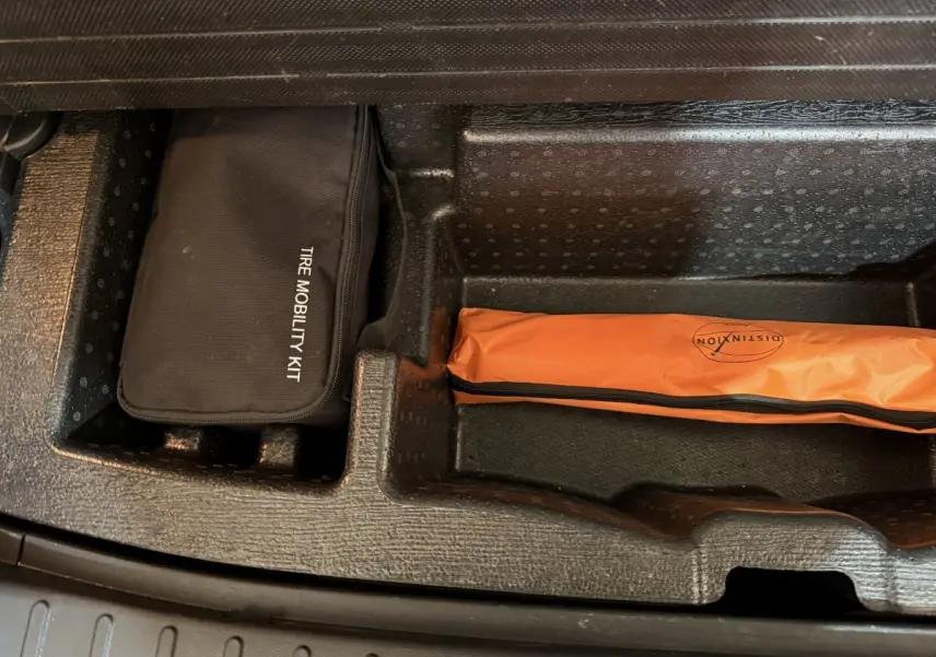 Compartiment de coffre du Hyundai Tucson 2021 noir avec kit mobilité pneus noir et trousse orange de sécurité.