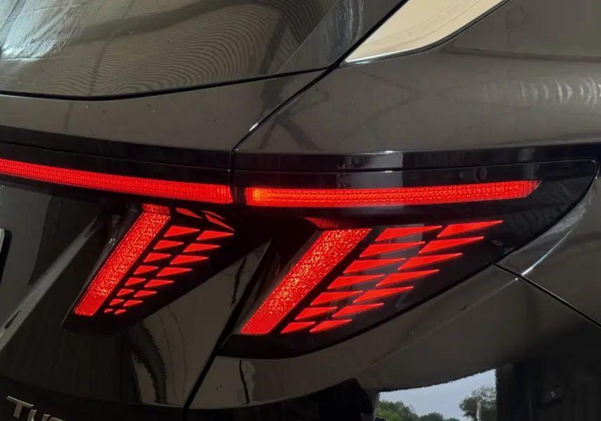 Feu arrière droit allumé du Hyundai Tucson noir 2021, soulignant son design lumineux distinctif en forme de flèches.