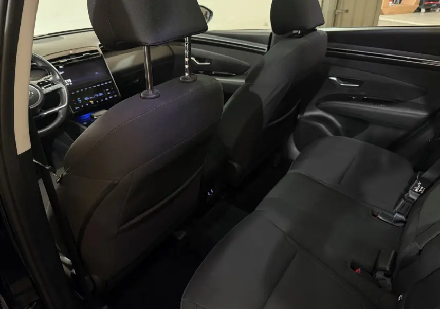 Intérieur noir du Hyundai Tucson 2021 vu depuis la porte arrière gauche, montrant les sièges arrière et le tableau de bord avant.