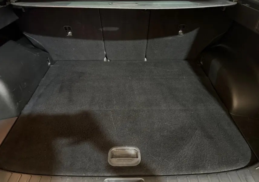 Coffre noir du Hyundai Tucson 2021 vu de face, montrant l'espace de chargement avec tapis et sièges arrière rabattus.