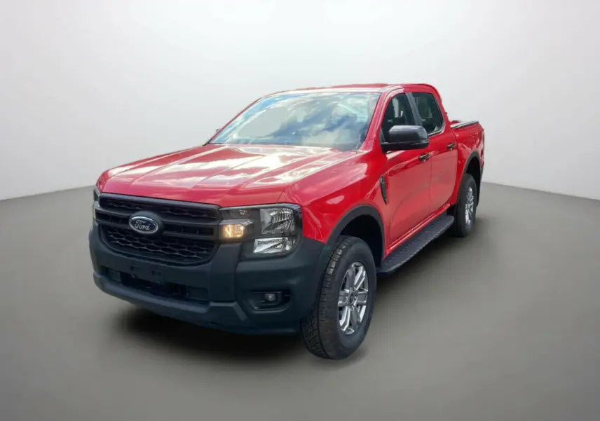 Ford Ranger 2025 rouge racing en 3/4 avant droit, avec calandre noire et phares allumés sur fond neutre.