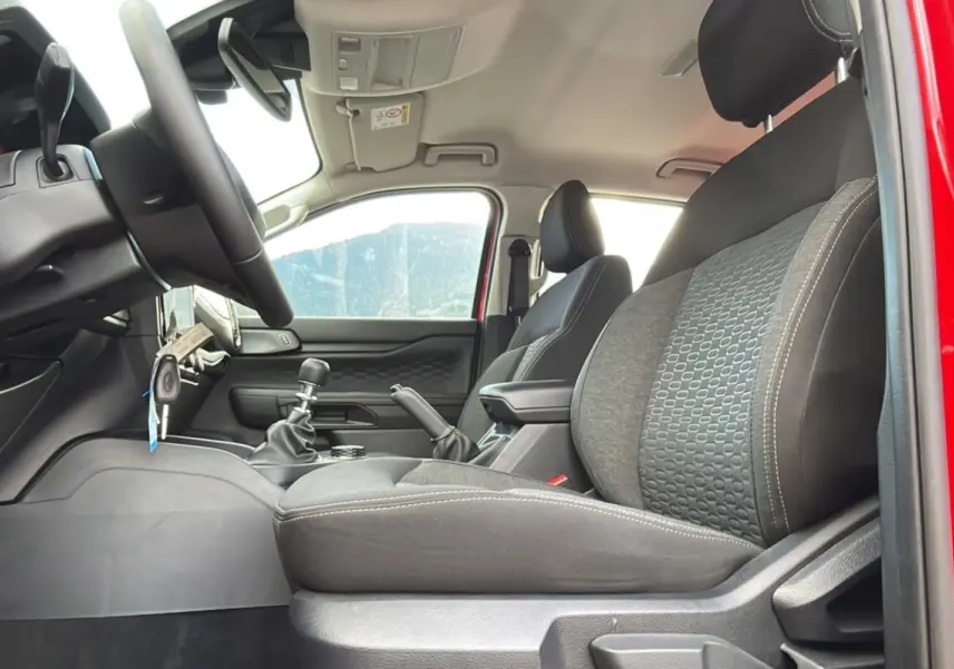 Intérieur du Ford Ranger 2025 rouge racing, vue côté gauche sur sièges avant et levier de vitesses manuel.