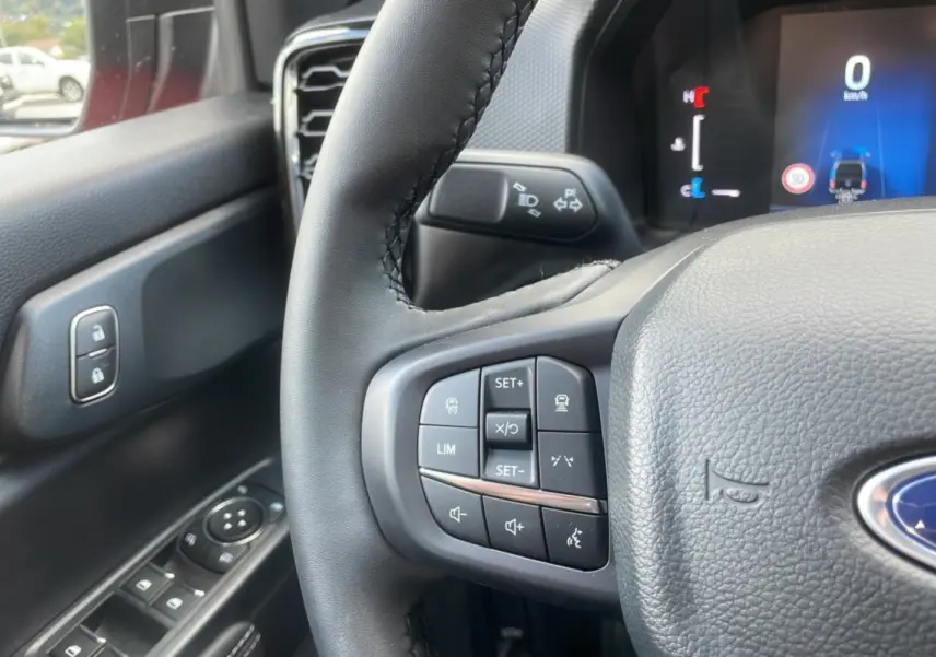Gros plan sur le volant noir du Ford Ranger 2025 avec commandes intégrées et tableau de bord numérique visible.