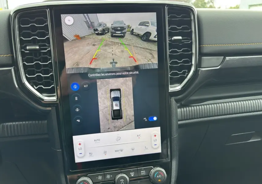 Écran central tactile du Ford Ranger 2025 montrant la caméra de recul et les commandes de climatisation, intérieur noir avec surpiqûres jaunes.