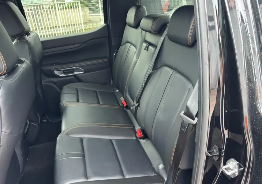 Vue intérieure côté droit sur la banquette arrière en cuir noir avec surpiqûres orange du Ford Ranger 2025 noir agate.