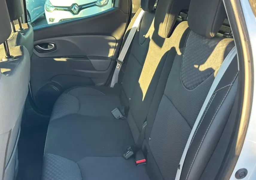Vue intérieure côté droit montrant la banquette arrière noire de la Renault Clio IV blanche de 2016.