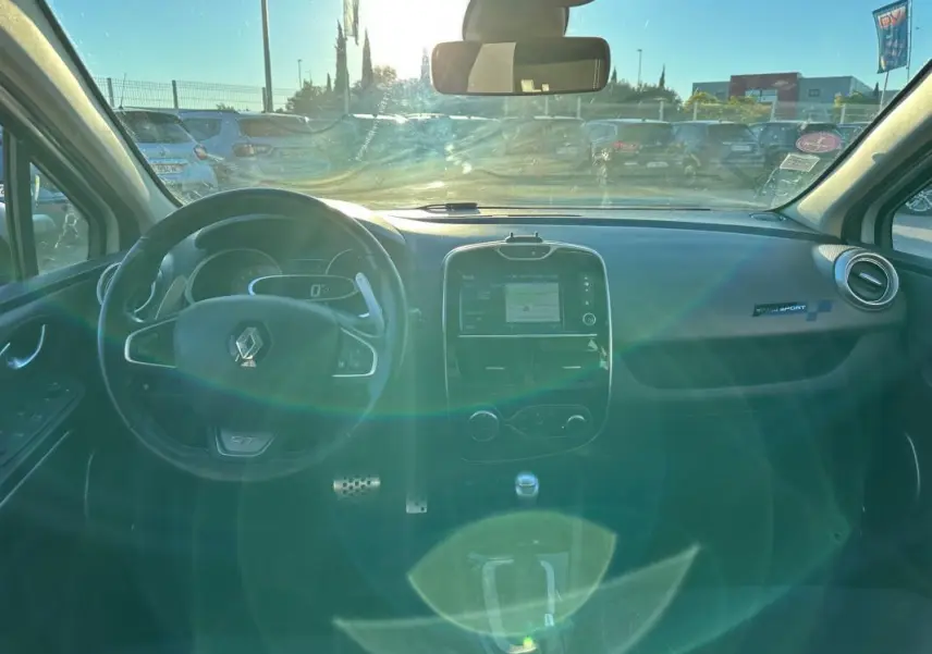 Intérieur avant de la Renault Clio IV TCe 120 GT EDC blanc, tableau de bord avec écran tactile et volant cuir sport.