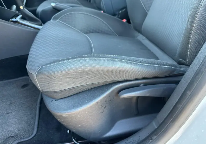 Gros plan sur le siège conducteur en tissu gris foncé de la Renault Clio IV TCe 120 GT EDC blanc, avec réglage manuel.