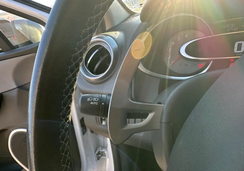 Gros plan sur le volant cuir et le tableau de bord de la Renault Clio IV blanche, avec compteur digital et lumière naturelle.