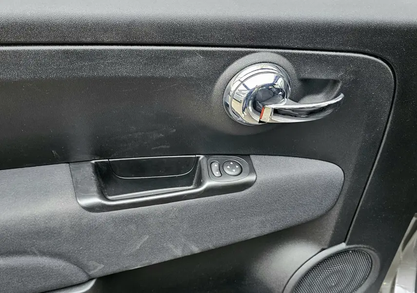 Poignée de porte intérieure chromée côté droit de la FIAT 500 gris 2023 avec commandes électriques des rétroviseurs.