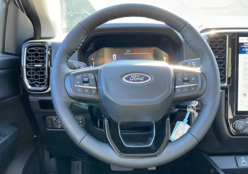Vue intérieure centrée sur le volant cuir multifonctions du Ford Ranger 2025 avec tableau de bord digital et écran tactile.