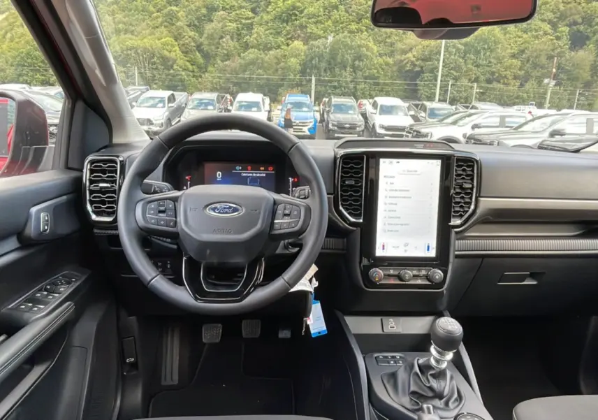Vue intérieure centrée sur le volant et la console centrale du Ford Ranger rouge racing, avec boîte manuelle et écran tactile.