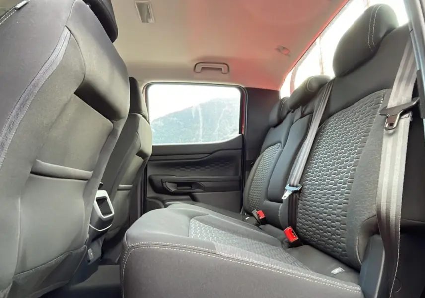 Vue intérieure arrière du Ford Ranger 2025, sièges noirs avec motifs texturés et ceintures de sécurité visibles.