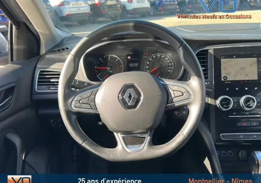 Vue intérieure centrée sur le volant Renault d'une Mégane IV Berline, tableau de bord et écran tactile visibles.