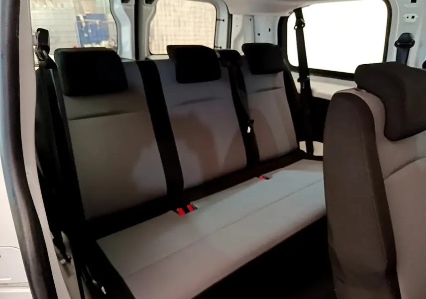 Vue intérieure côté gauche du Peugeot Traveller 2018 blanc, montrant la banquette arrière grise avec appuie-têtes noirs.