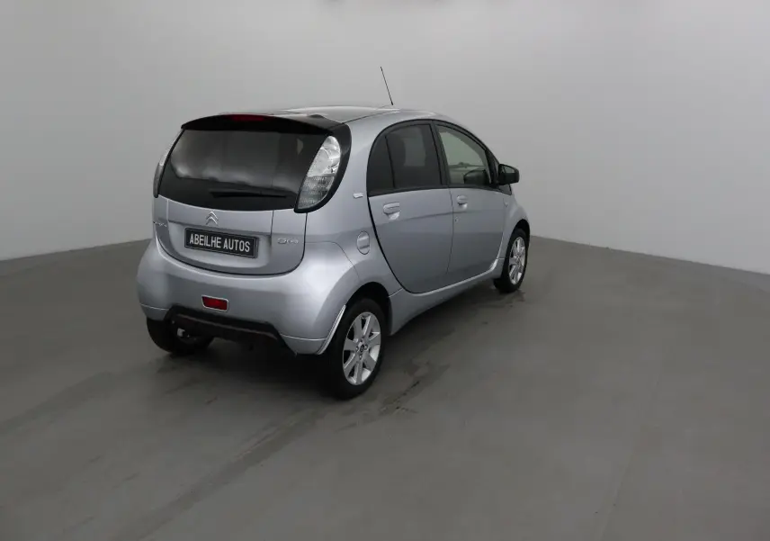 Vue 3/4 arrière droite d'une Citroën C-ZERO gris alu électrique, compacte et moderne dans un studio neutre.
