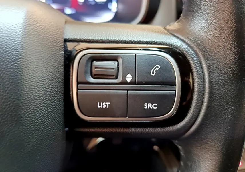 Gros plan sur les commandes au volant à gauche du Citroën C5 Aircross 2020, cuir noir et boutons fonctionnels.