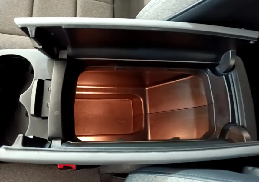 Vue plongeante sur l'accoudoir central ouvert du Citroën C5 Aircross gris foncé, révélant un espace de rangement intérieur.