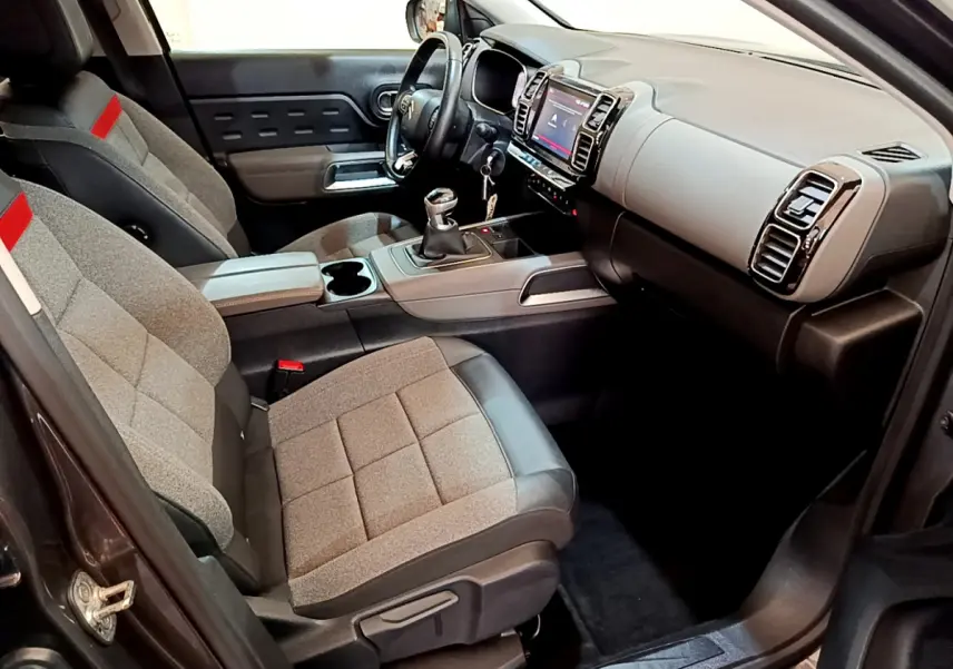 Intérieur avant droit du Citroën C5 Aircross gris foncé 2020, sièges tissu Stone Grey avec cuir noir et console centrale manuelle.