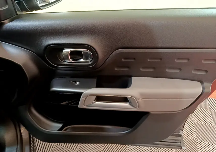 Gros plan sur la porte intérieure côté gauche du Citroën C5 Aircross 2020 gris foncé avec accoudoir beige et poignée chromée.