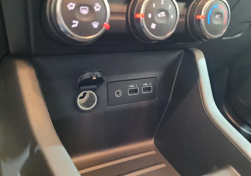 Gros plan sur la console centrale noire de la Renault Clio gris foncé montrant les commandes de climatisation et ports USB.