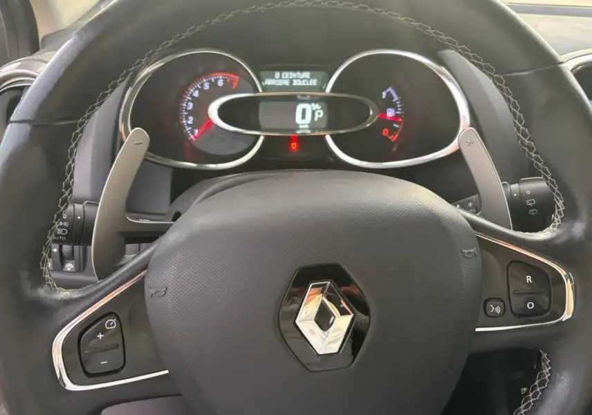 Vue rapprochée du volant cuir noir de la Renault Clio IV Estate avec commandes intégrées et tableau de bord digital.