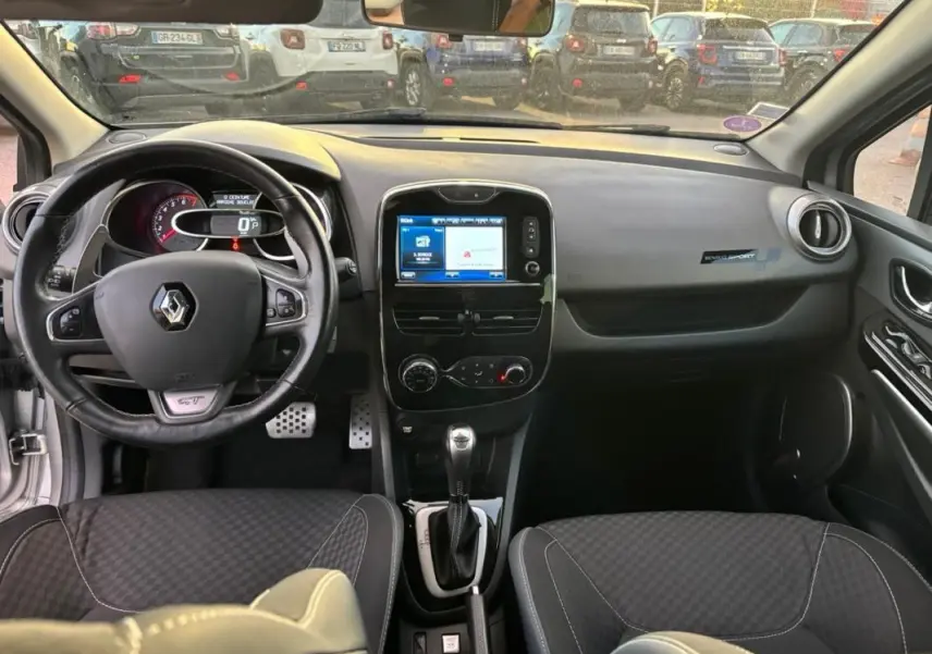Vue intérieure avant de la Renault Clio IV Estate gris clair, volant cuir GT, écran tactile et levier de boîte automatique.