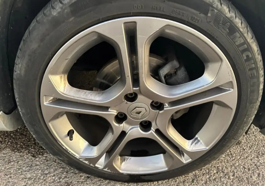 Gros plan sur la jante alliage 17 pouces gris clair d'une Renault Clio IV Estate TCe 120 GT EDC avec logo Renault central.