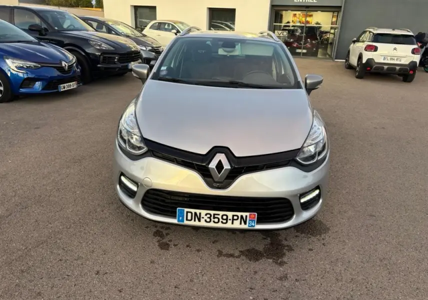 Vue avant d'une Renault Clio IV Estate gris clair avec calandre noire et feux diurnes LED allumés.