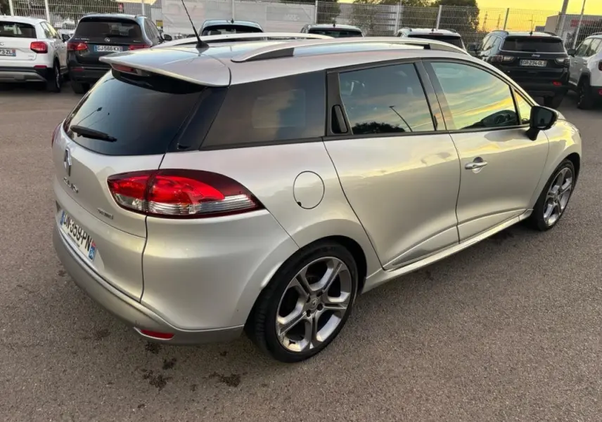 Vue 3/4 arrière droite d'une Renault Clio IV Estate gris clair avec jantes alliage 17 pouces et vitres surteintées.