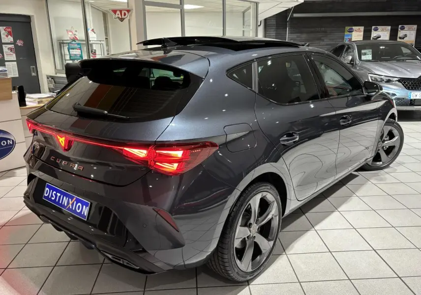 Vue 3/4 arrière droite d'une CUPRA Leon gris Graphène avec feux arrière Tri-LED et toit ouvrant panoramique.